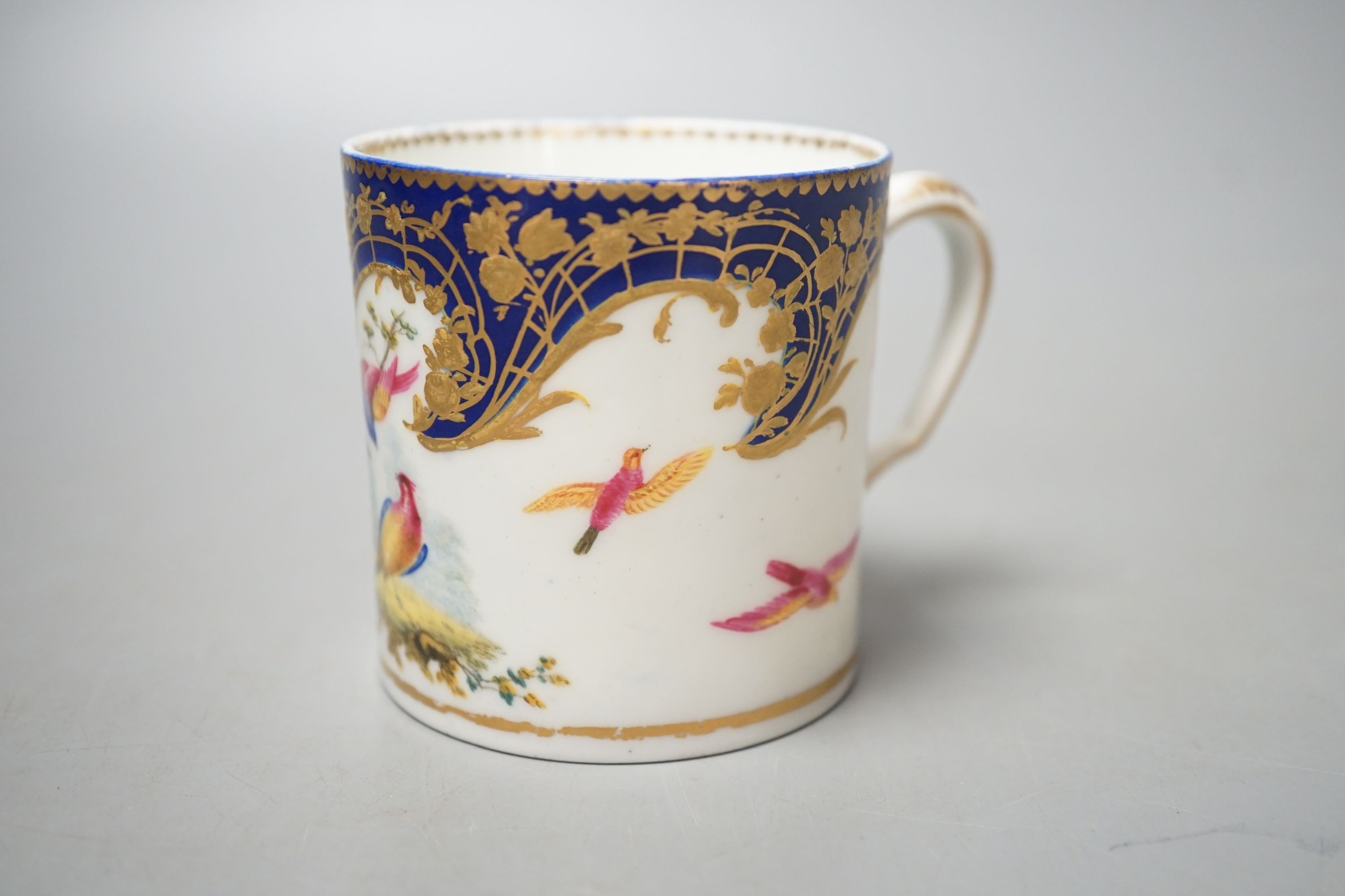 A Sevres coffee can painted with two birds in a tree, and other birds in flight under a richly gilded blue ground date code for 1766